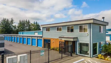 Self-storage facility with a two-story office building and rows of blue storage units.